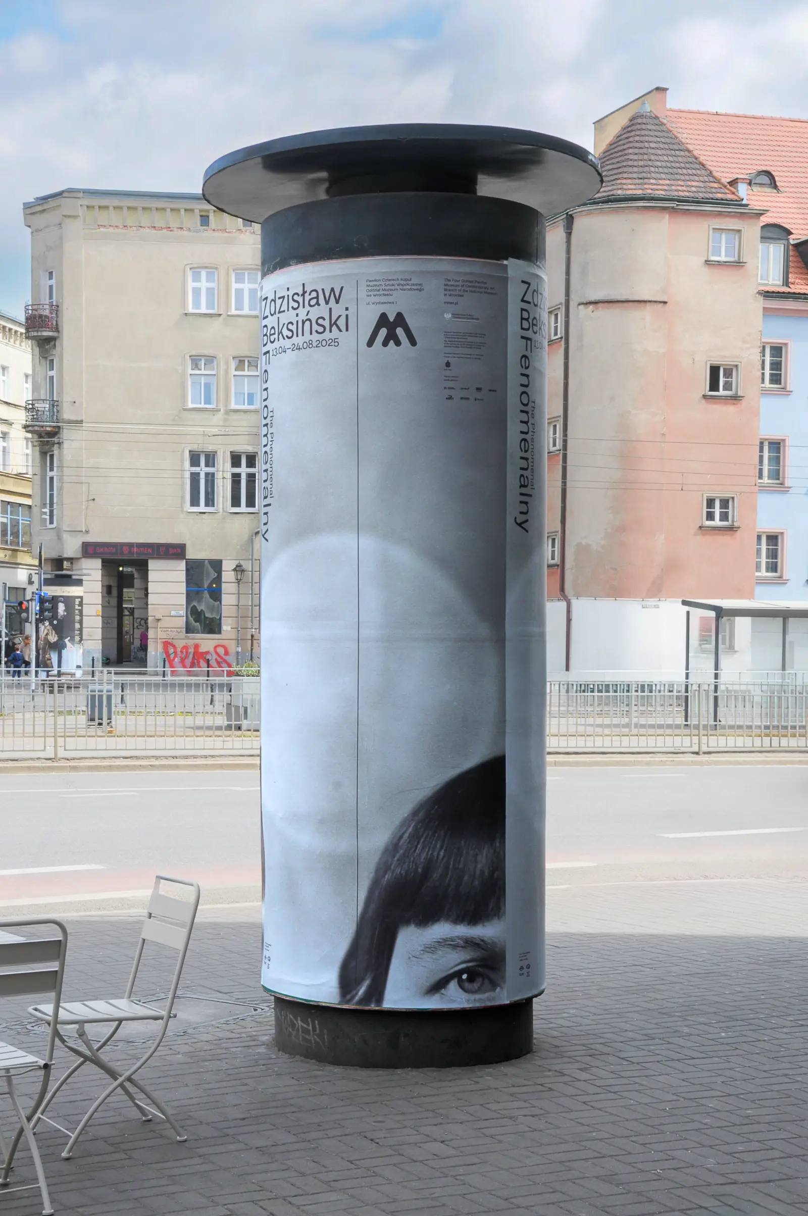 Plakat wystawy „Fenomenalny. Zdzisław Beksiński” na słupie plakatowym na ulicy Wrocławia.
