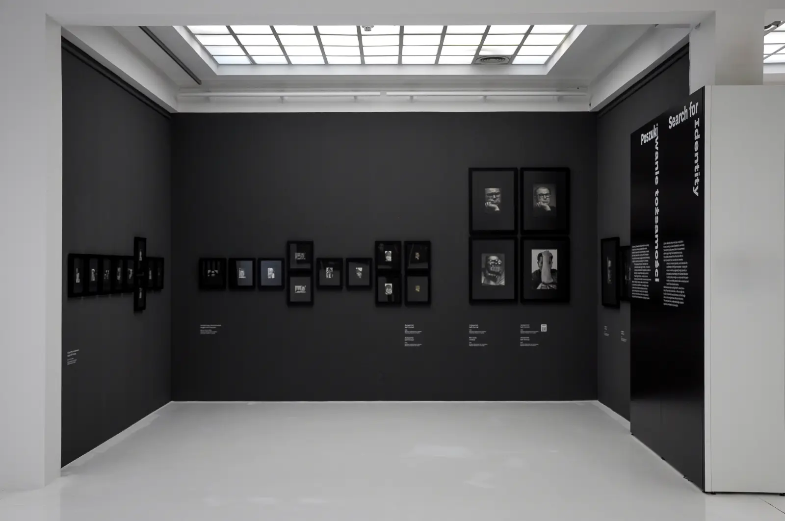 Widok wystawy „Fenomenalny. Zdzisław Beksiński”. Czarna sala z czarno-białym autoportretami artysty.