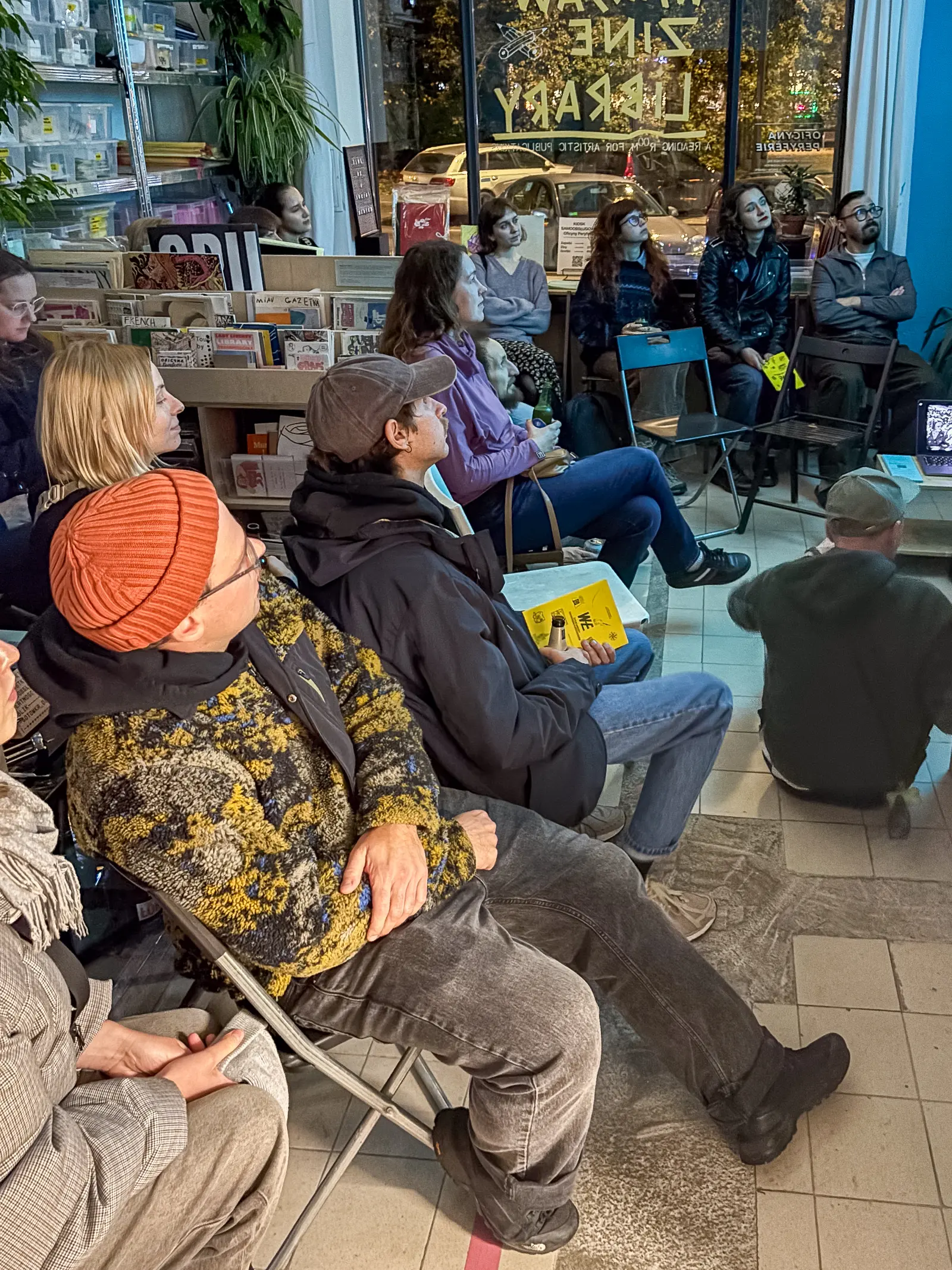 Premiere of the zine. The audience sitting on chairs and on the floor.