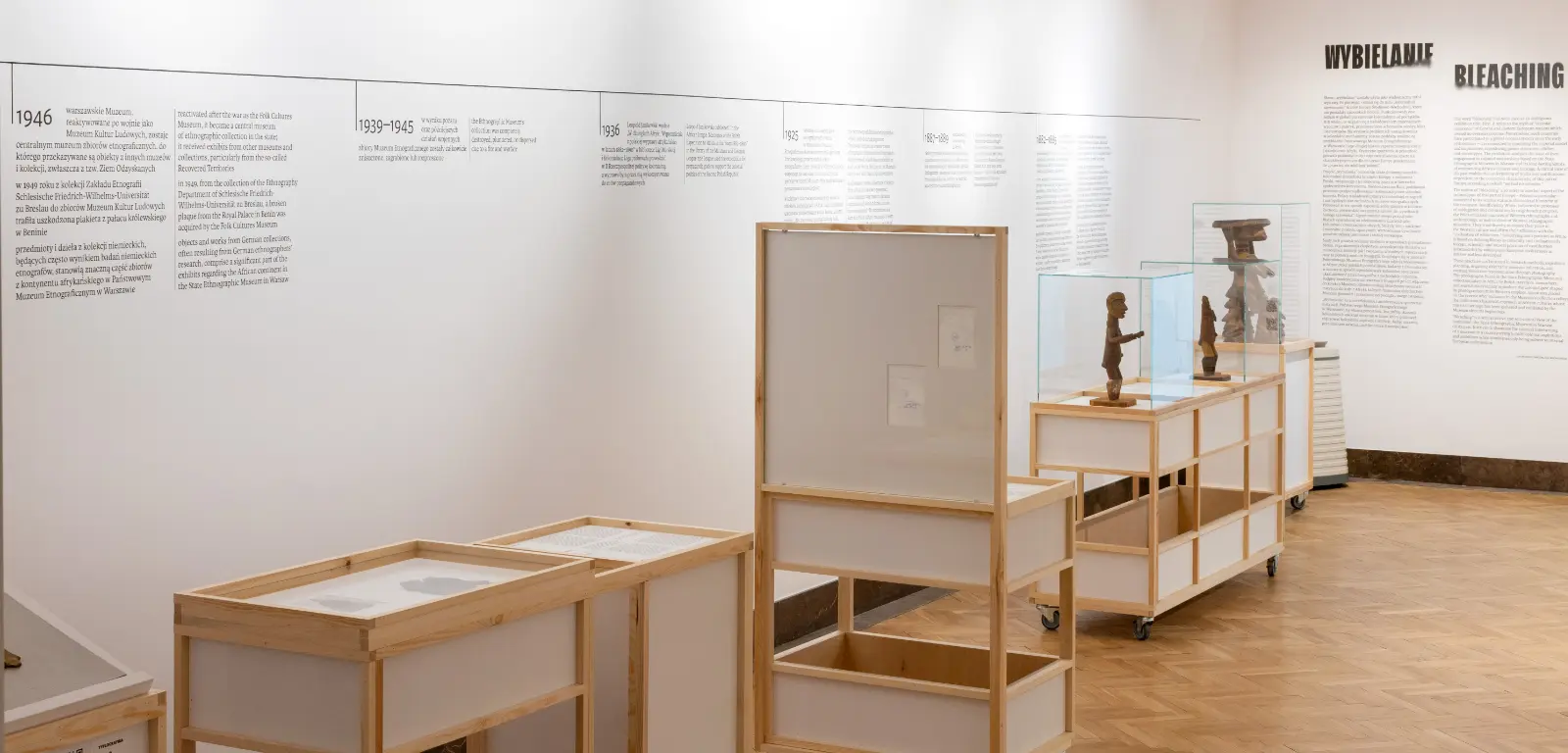 View of the exhibition. Text printed on the walls in the background. Display cases with artifacts in the foreground.